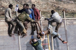 An African migrant is lowered from a border fence by a Spanish Civil Guard at the border between Morocco and Melilla during the latest attempt to cross into Spanish territory