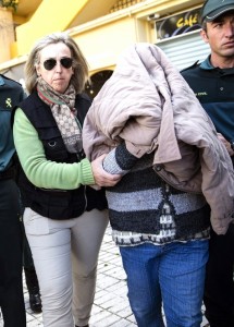 The accused covers her face after arrest in 2014