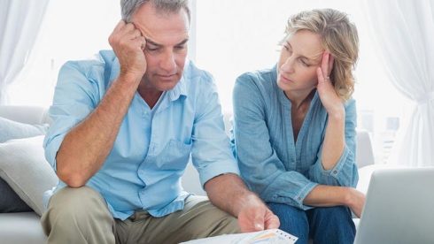 Concerned Senior Couple On Couch With Bills Mst