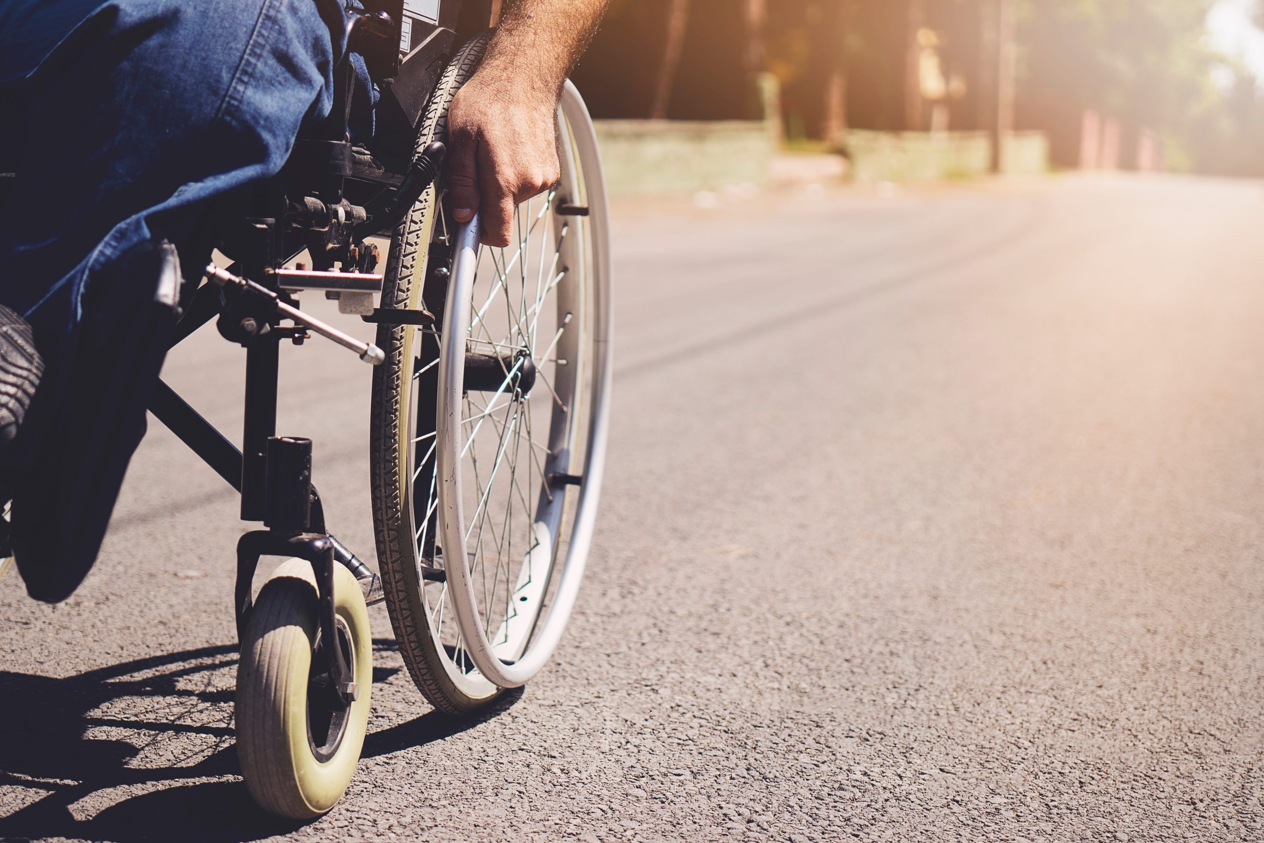 Young Disabled Man In Wheelchair Walking Park