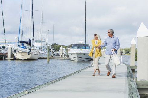 Happy Senior Couple Walking Along Harbor Holding Hands