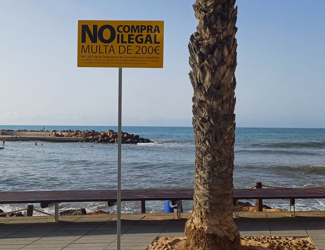 Warning signs tell tourists about €200 fines if they buy from looky looky men on Spain's Costa Blanca