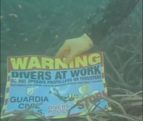 Guardia Civil divers place a sign on the unexploded device